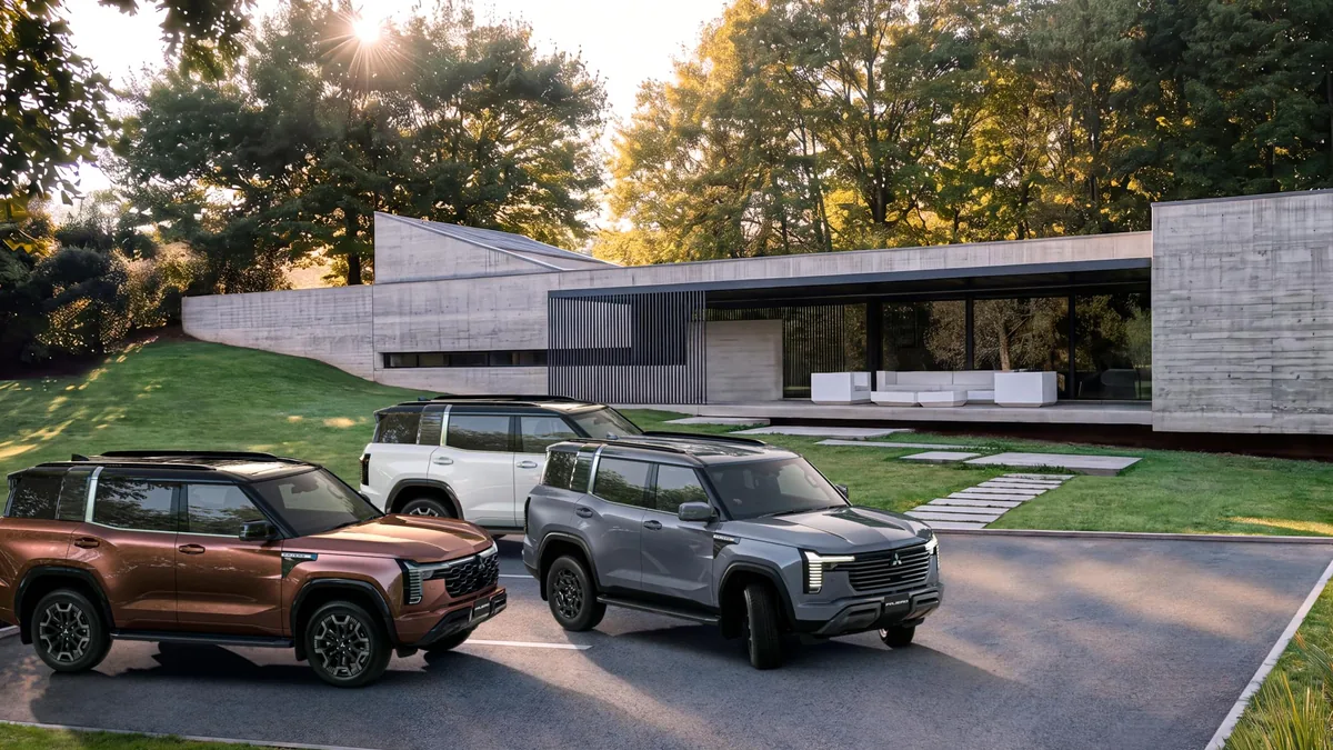 新型パジェロ3台が建物の前の駐車スペースに並ぶ公式写真。ブロンズ系・グレー系・白系の車体