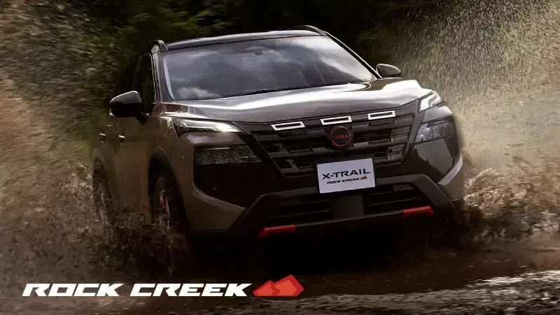 Rock Creekグレードのエクストレイルが、水しぶきを上げて林道を進む正面の外観