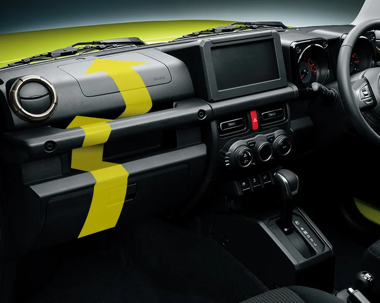 ジムニーの運転席まわりを斜め上から写した内装。黄色のアクセントが入ったダッシュボードにディスプレイとエアコン、シフトレバーが並ぶ公式写真