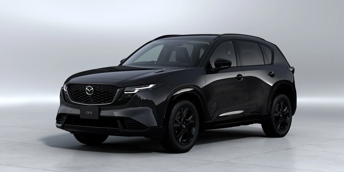 黒い新型CX-5を左斜め前から見た外観。明るいスタジオの背景に、細いヘッドライトと黒いホイールが見える