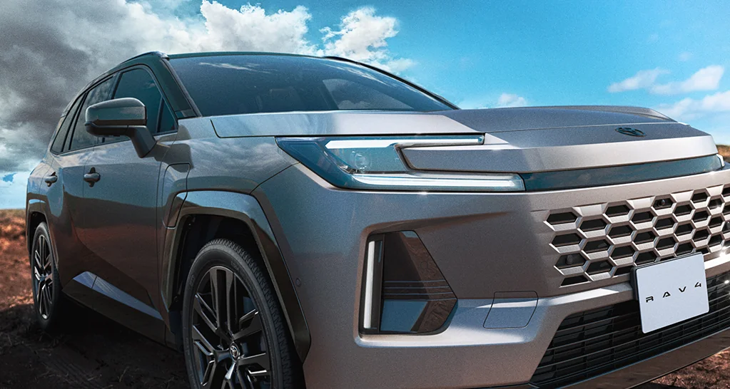 青空の下にいるグレーのRAV4を斜め前から見た外観。ヘッドランプと六角形のフロントグリル、ナンバー位置のRAV4のプレートが見える
