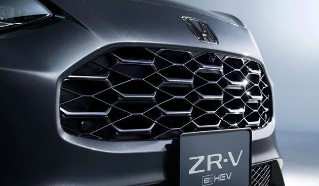 濃いグレーのZR-Vのグリルを近くから見た写真。六角形を重ねた形の格子と、その上のHマークが写る