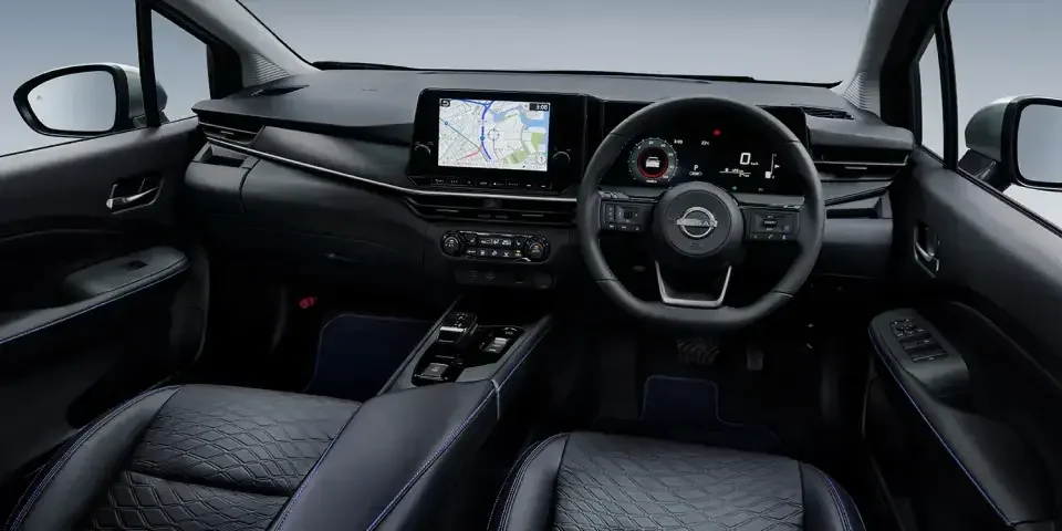 AUTECH CROSSOVERの運転席まわり。黒いダッシュボードに横長の画面とメーターが並び、手前のシートにはひし形の模様と青いステッチが入る