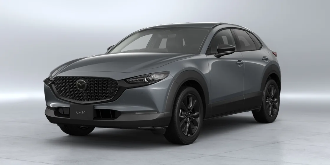 明るいスタジオに置いた灰色のCX-30を左斜め前から見た外観。黒いメッシュのグリルと、黒いホイールが分かる