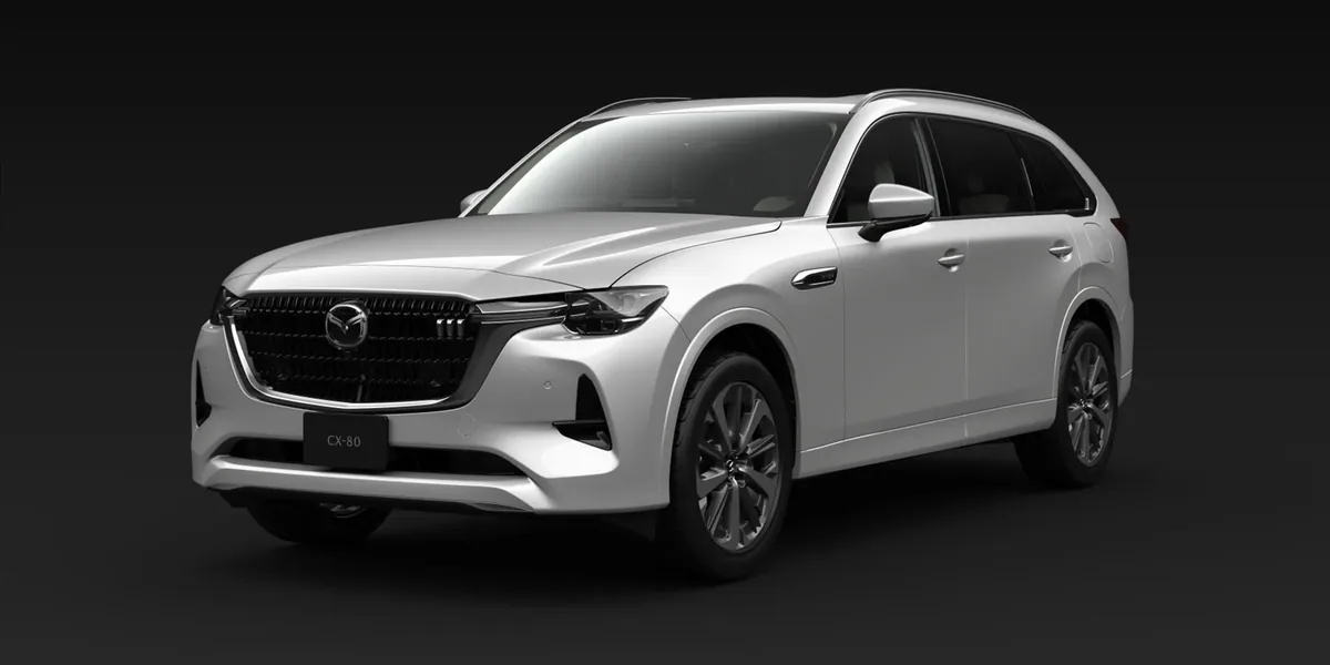 暗い背景に置いた白いCX-80を左斜め前から見た外観。大きなグリルと黒いホイールが見える