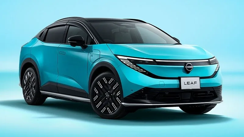 日産リーフを斜め前から見た外観。ターコイズのボディに黒いルーフで、細く光る横一文字のランプの下に日産のエンブレムと「LEAF」のプレートが付く