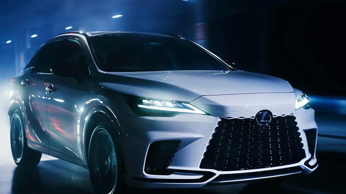 夜の道を走る白いレクサスRXの外観。前面のスピンドルグリルとヘッドランプが光っている