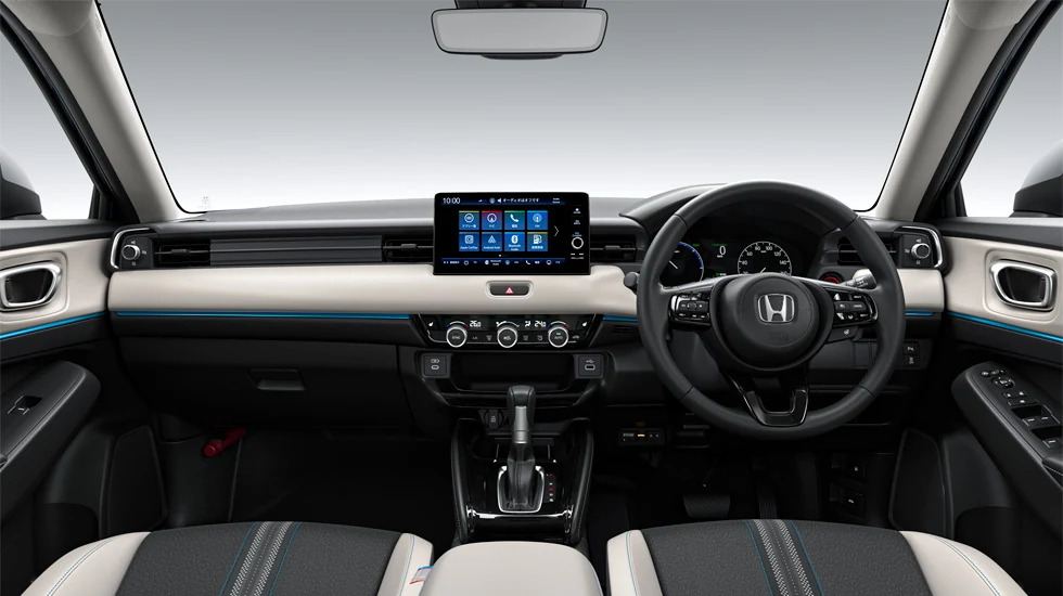 ヴェゼルの運転席まわりを後ろ寄りから見た室内。中央に大きなナビ画面と丸いステアリング、ベージュのインパネ、前席シートの上端が見える