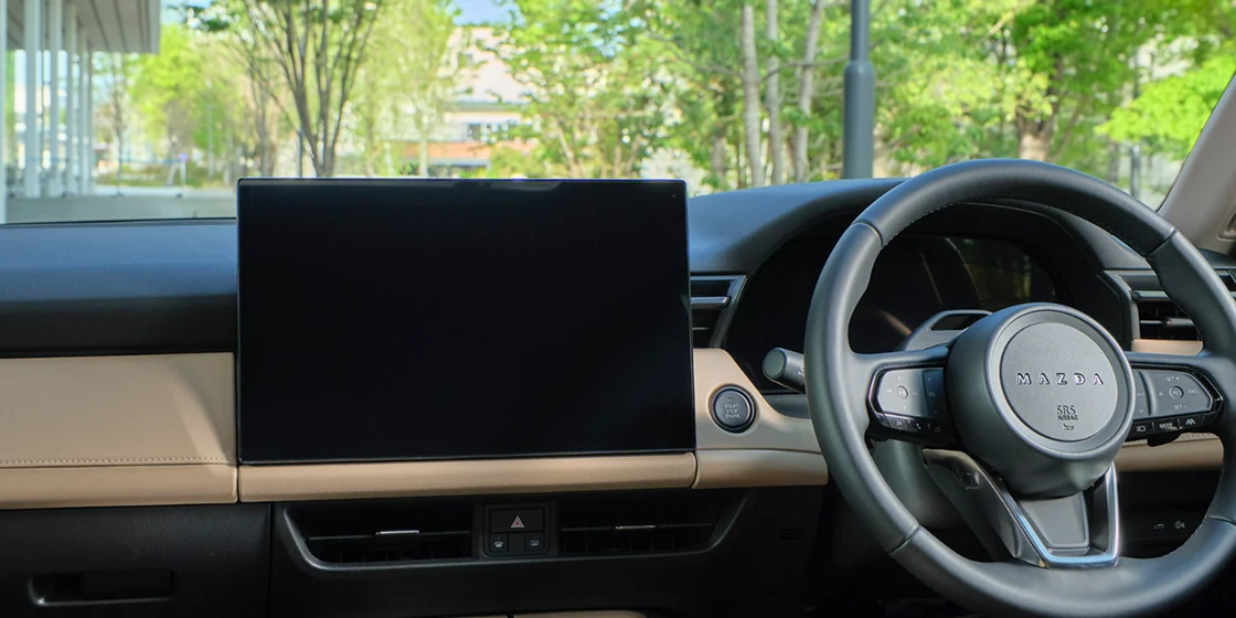 新型CX-5のダッシュボード。中央に横長の大きなディスプレイが立ち、右にステアリングがある。下半分はベージュ色