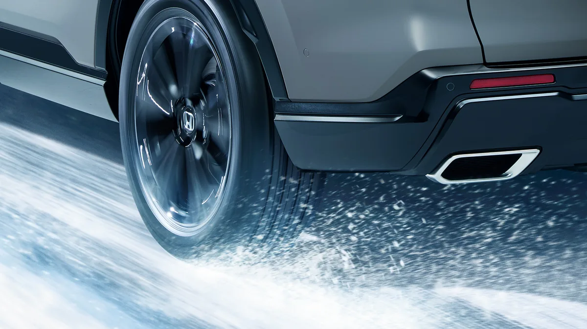 CR-V（6代目）の後輪まわり。タイヤが雪を巻き上げ、後ろにマフラーの先が見える