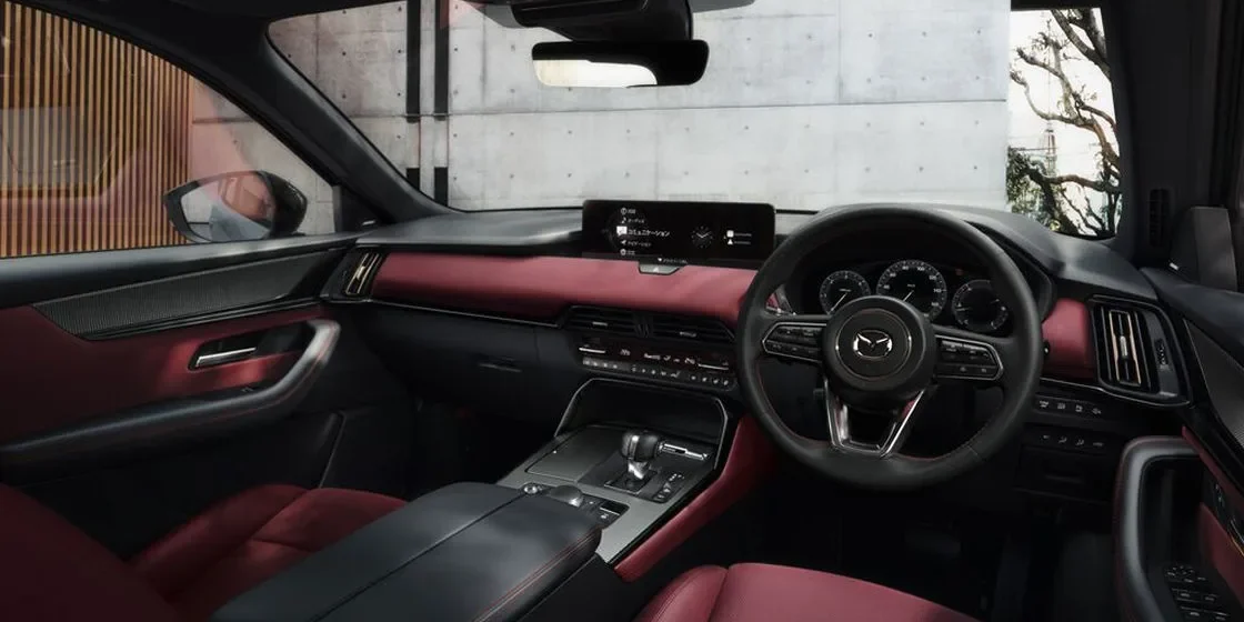 CX-60の運転席まわり。赤い内装のダッシュボードの中央に横長のディスプレイがあり、右側にステアリングとメーターが見える