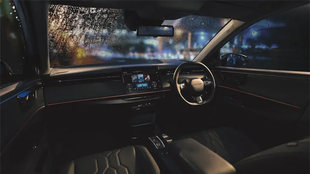 夜の雨の街を背にしたインサイトの運転席まわり。2本スポークのハンドル、中央のディスプレー、ドアに沿って光る赤い線が見える