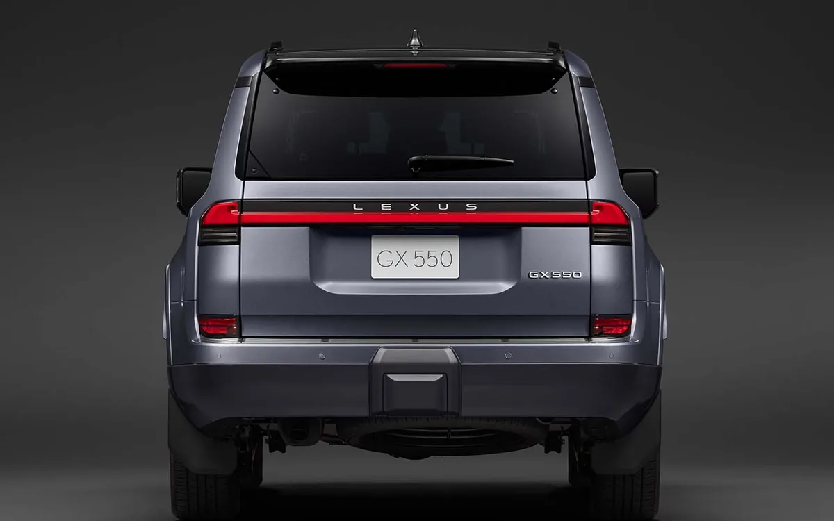 暗い背景に置かれたレクサスGX550の後ろ姿。横一本につながった赤いテールランプとLEXUSの文字、GX 550のナンバープレートが見える