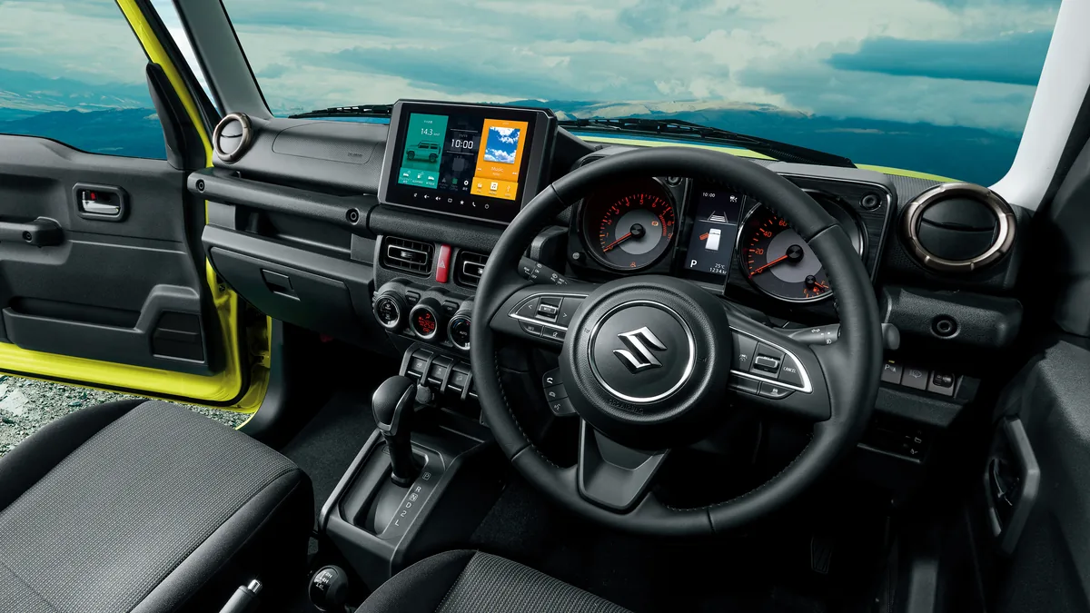 ジムニーの運転席まわり。黒いステアリングと中央の大きなディスプレイ、4ATのシフトレバーが見える