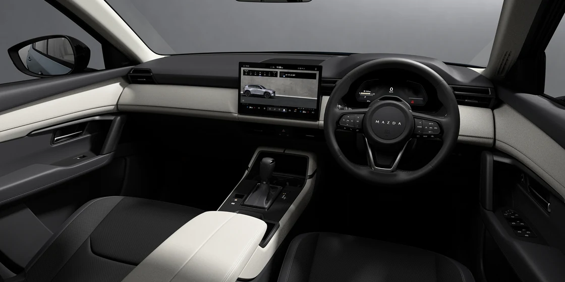 黒と白っぽい色でまとめた新型CX-5の運転席まわり。中央に大きなディスプレイ、右にステアリング、手前にシフトレバーが見える