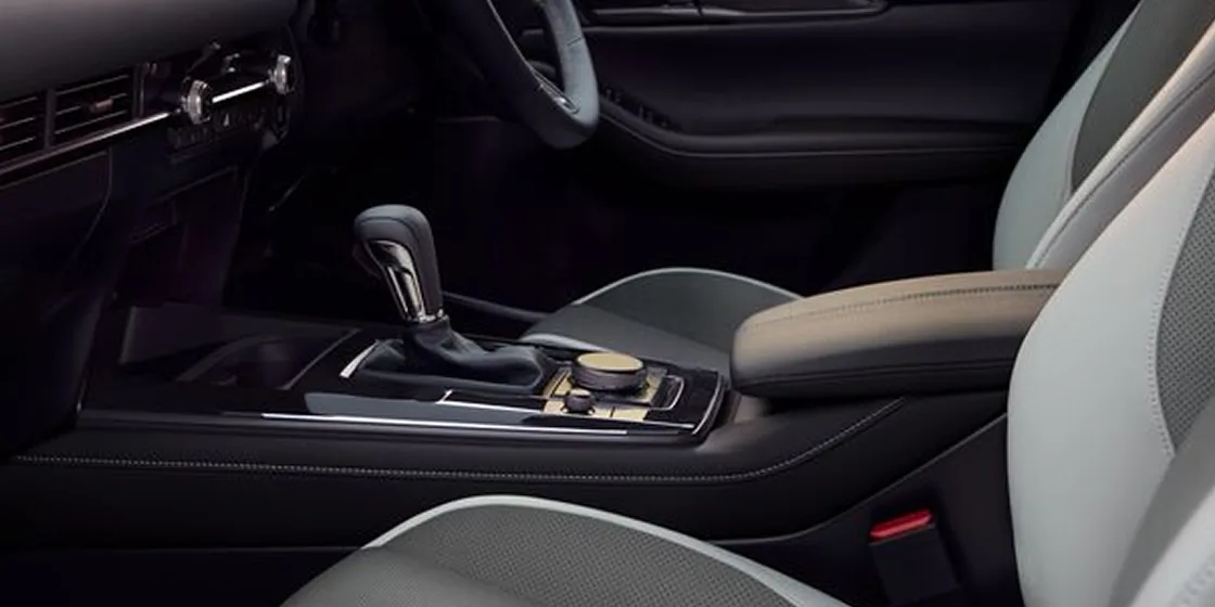 CX-30の前席の間にあるシフトレバーと丸いダイヤルのアップ。左右に明るい灰色のシートがある