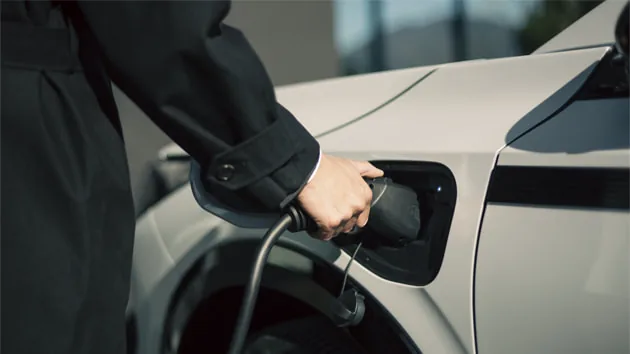 白いインサイトの車体の充電口に、充電ケーブルのコネクターを差し込んでいる手元