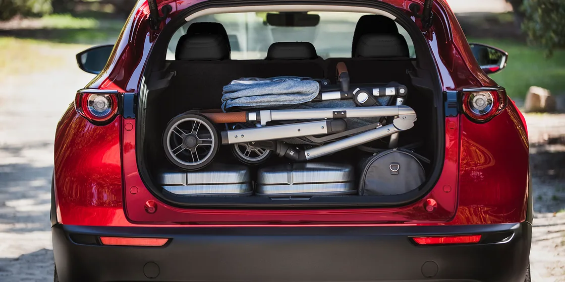 赤いCX-30のリアゲートを開け、荷室にたたんだベビーカーと荷物を積んだ様子を真後ろから写したもの