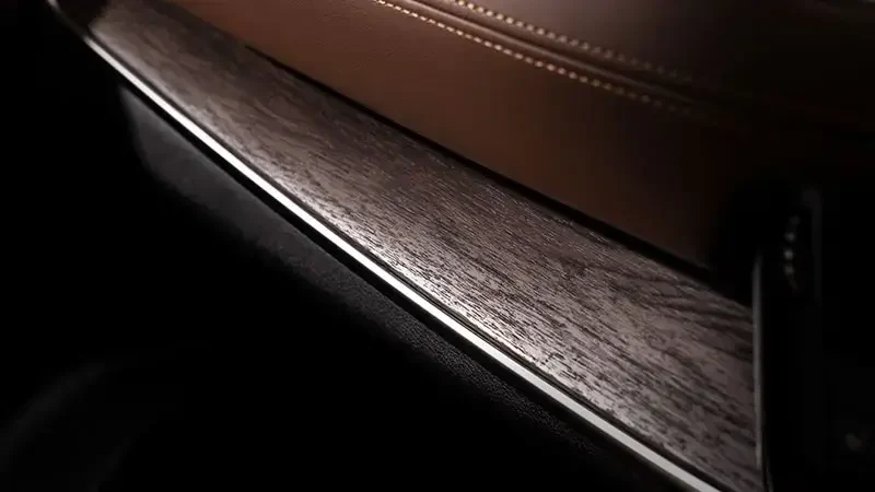 エクストレイルの内装の木目調の加飾パネルの接写。茶色の革張りの縁に沿って、木目調の帯と銀色の細い線が走っている