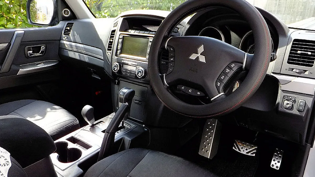 4代目パジェロ（ショートボディ・2012年型）の運転席まわり。ハンドルカバーを付けたステアリング、ナビ画面、シフトレバーが見える