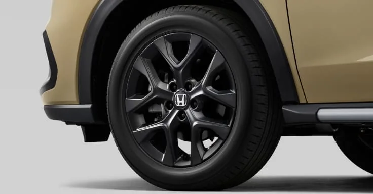 ベージュのZR-Vの左前輪まわり。黒いホイールと、車体の下側を縁取る黒い樹脂とシルバーの部品が見える
