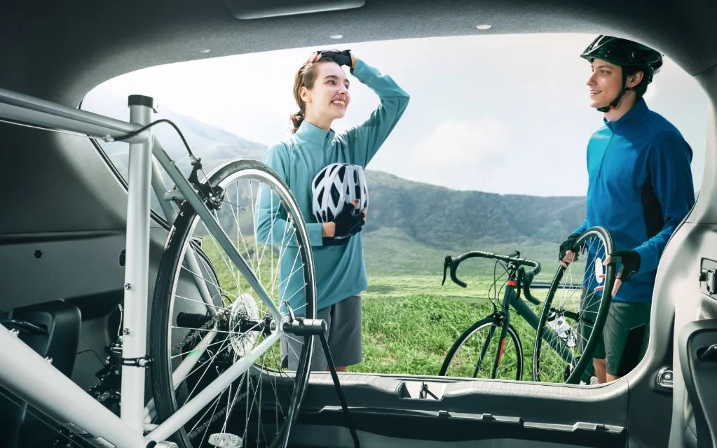 ヤリス クロスのリアゲートを開けた荷室から外を見た様子。自転車が積まれ、荷室の向こうで2人が自転車を持って話している
