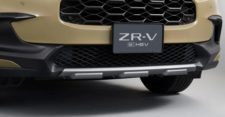 ベージュのZR-Vの前バンパーの下側。六角形を重ねたグリルの下に、黒い樹脂とシルバーの横長の部品が付く