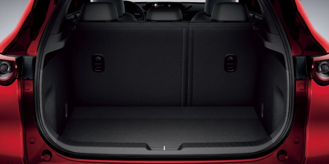 赤いCX-30のリアゲートを開けた荷室。何も積んでいない平らな床の奥に、後席の背もたれが立っている