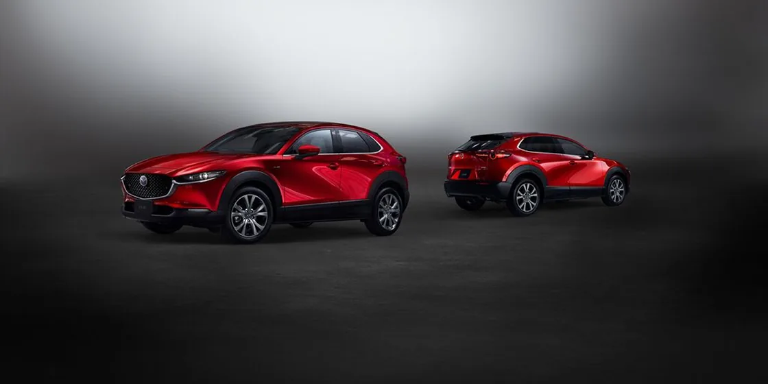 暗いスタジオに赤いCX-30が2台並ぶ様子。手前の1台は左斜め前から、奥の1台は右斜め後ろから写っている