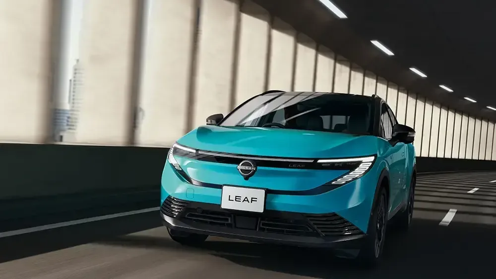 トンネルの中を走るターコイズの日産リーフを前から見た外観。細く光る横一文字のランプと「LEAF」のプレートが付く