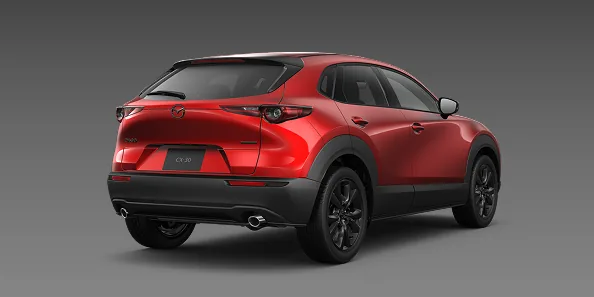 灰色の背景に置いた赤いCX-30を右斜め後ろから見た外観。横長のテールランプと、左右に分かれたマフラーの出口が分かる